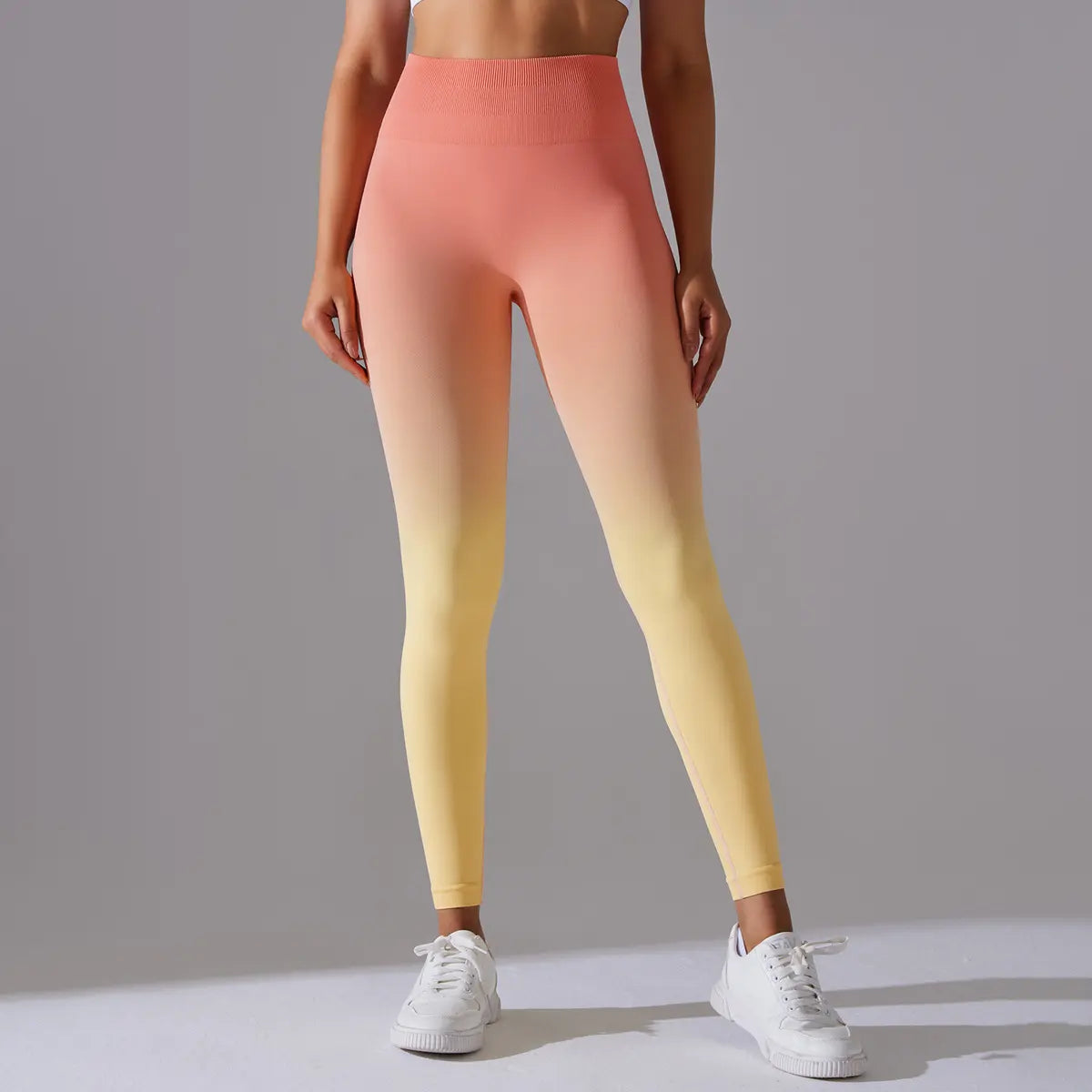 Person wearing a gradient melange yoga pants leggings from orange to yellow on a gray background